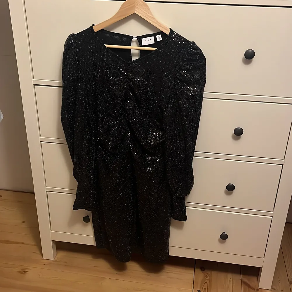 Nyskick, köpte för 700 och säljer för 350💗Snygg svart glittrig klänning från Vila i storlek S. Perfekt nu till nyår eller jul  med sitt glittrande material som fångar ljuset. Klänningen har en elegant passform och långa ärmar, vilket gör den idealisk för både höst och vinter. Ett måste för garderoben om du vill sticka ut på nästa fest! ✨. Klänningar.