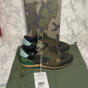 Valentino Rockrunner - Säljer ett par Valentino Rockrunner sneakers de är i storlek 41men passar 42i camouflage. Skorna har en cool mix av grönt, brunt och svart med detaljer i mocka och skinn. De har en unik design med snörning och en grön häl med nitar. Perfekta för att sticka ut i mängden! 