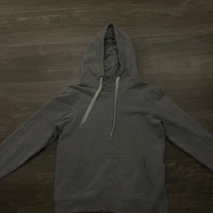Grå hoodie - Säljer en stilren grå hoodie i bra skick. Den har en klassisk design med känguruficka och justerbar huva med vita snören. 💞 Tveka inte och ställ frågor!! 🥰