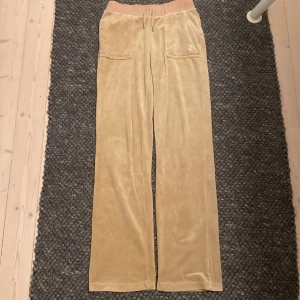Beige mjukisbyxor från Juicy Couture - Säljer ett par supermysiga beige mjukisbyxor från Juicy Couture i storlek XS. Två små fläckar finns längst ner på benet, därav priset. Utöver det är dom fortfarande i bra skick.