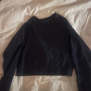 Svart tränings topp - Säljer en svart tränings topp. Perfekt för höst och vår, med långa ärmar som håller dig varm. Enkel och stilren design som passar till det mesta. Perfekt för en casual look eller att klä upp med accessoarer.