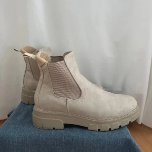 Beige Chelsea boots - Snygga beige Chelsea boots i mocka med elastiska paneler på sidorna för enkel på- och avtagning. Perfekta höst/vinter boots, mycket bekväma och varm värdering inuti! Bootsen är från DinSko , märket SoAll. Endast använda en gång därav mycket bra skick!