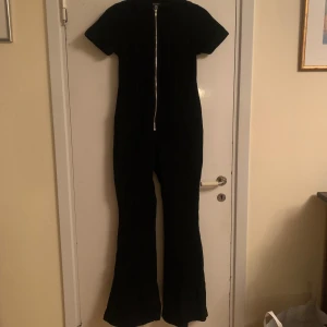 Svart jumpsuit från Boohoo - Snygg svart jumpsuit från Boohoo i storlek XS. Den har en dragkedja framtill och korta ärmar. Säljs pga för liten. Skriv privat för fler bilder eller frågor! 🍁öppen för prutning 