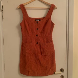 Orange manchesterklänning - Jättefin orange manchesterklänning från Reclaimed Vintage. Klänningen har knappar framtill och fickor! Säljs pga passar inte längre. Skriv privat för fler bilder eller frågor🍁öppen för prutning 