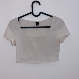 Vit croppad topp - Säljer en superfin vit croppad topp från Urban Outfitters. Den har en enkel och stilren design med korta ärmar och en rundad halsringning. Perfekt för sommardagar eller att matcha med en högmidjad kjol. Toppen är i bra skick och redo för nya äventyr!