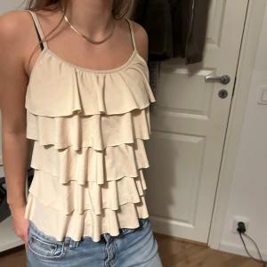 Snygg volangtopp! - Säljer en superfin beige topp med volanger. Toppen är i bra skick och passar både till vardags och fest💕