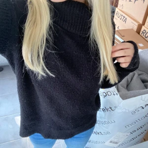Svart stickad polotröja - Mysig svart stickad polotröja perfekt för kyliga dagar. Den har en hög krage och långa ärmar, vilket gör den superbekväm och varm. Passar perfekt till jeans för en avslappnad look. Perfekt för höst och vinter!