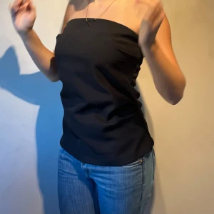 Svart tub topp - Svart tub topp med tightare midja och vidare nedtill, fina vikningar och detaljer.  Denna är förstor för mig och det är därför jag säljer den😊 Aldrig använd.