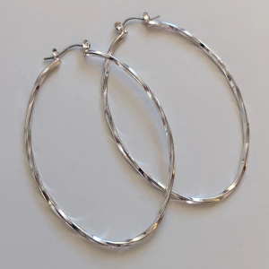 Stora silverfärgade hoop-örhängen - Stora och snygga hoop-örhängen i silverfärg. De är ovala och har en elegant, vriden design som fångar ljuset fint.nyskick