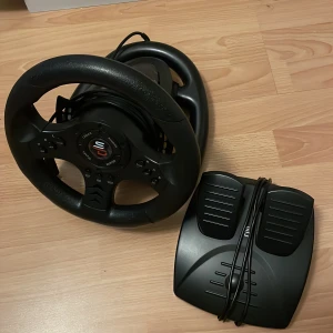 Ratt och pedaler Superdrive SV 450 - Säljer en Superdrive SV 450 ratt och pedaler för gaming. Ratten är svart med en sportig design och flera knappar för olika funktioner. Pedalerna är också svarta och har en realistisk känsla. 