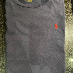 Mörkblå Polo Ralph Lauren T-shirt - Storlek S - Röd logga - Säljer en mörkblå Polo Ralph Lauren T-shirt i storlek S med en röd logga. T-shirten är använd men i mycket bra skick, utan några defekter eller skador. Bara texten. Stilren och bekväm t-shirt av hög kvalitet som passar till det mesta.