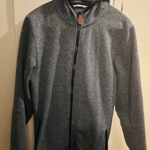 Grå fleecejacka från H&M - Säljer en blå fleecetröja från H&M i storlek 14Y/170. Den har en dragkedja framtill och en mysig huva. Perfekt för kyliga höst- och vårdagar. Tröjan är i bra skick och superbekväm att ha på sig. Passar både till skolan och fritiden!