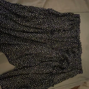 Svart prickig kjol - Säljer en superfin svart kjol med vita prickar. Den har en elastisk midja som gör den bekväm och lätt att bära. Perfekt för både vardag och fest!