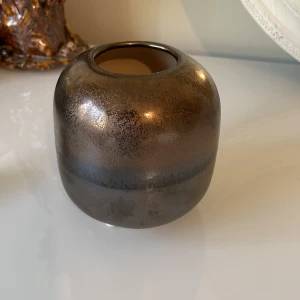 Brun vas från Bloomingville - Säljer en snygg brun vas från Bloomingville. Den har en rund form och en glansig yta som ger ett elegant intryck. Perfekt för att dekorera ditt hem med blommor eller bara som en stilren inredningsdetalj. Vasen är i fint skick och redo att hitta ett nytt hem!