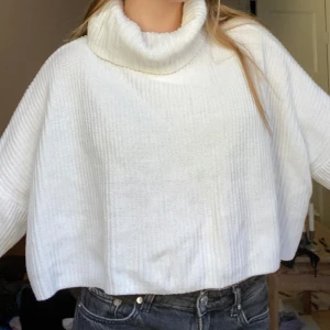 Vit stickad tröja från Hollister - Mysig vit stickad tröja från Hollister i storlek XS. Den har en croppad passform med polokrage och långa ärmar. Perfekt för kyliga dagar när du vill vara både varm och stilren. Passar bra till jeans eller leggings för en casual look.