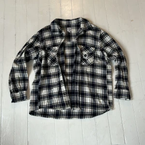Svartvit rutig skjorta/overshirt från Polar - Säljer en snygg svartvit rutig skjorta från Polar. Den har långa ärmar och två bröstfickor med knappar. Perfekt för höst och vår. Skjortan är i bra skick och gjord av mjukt material som känns skönt mot huden. Passar perfekt för en avslappnad stil!