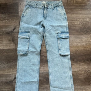 Blå cargopants i jeansmaterial - Säljer ett par snygga blå cargopants i jeansmaterial. De har en loose passform och är perfekta för en avslappnad stil. Byxorna har praktiska fickor på sidorna och en klassisk midwaist. Perfekta för både vardag och äventyr!