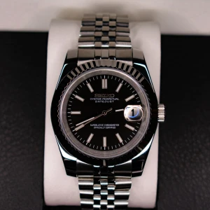 Seiko Datejust MOD  - Säljer en elegant Seiko Oyster Perpetual Datejust i svart och silver. Klockan har en stilren svart urtavla med datumvisning och en robust silverfärgad länkarmband. Perfekt för både vardag och fest. Den är i mycket bra skick och redo att bäras av nästa ägare! Besök gärna våran Instagram:KeeWeemods