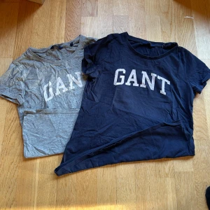 T-shirtar från GANT  - Två snygga t-shirtar från GANT i storlek XS. Den ena är grå och den andra svart, båda med GANT-loggan tryckt i vitt på framsidan. Perfekta för en casual look året runt. Gjorda i mjukt bomullsmaterial. 💙 använda men fortfarande i ett gott skick