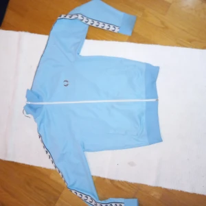 Ljusblå tröja från Fred Perry - Säljer en snygg ljusblå sportjacka från Fred Perry i storlek XS. Andvänd men i bra skick