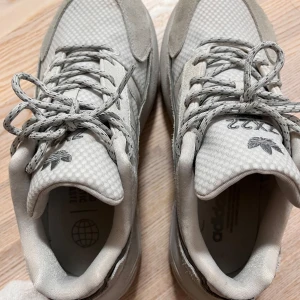Adidas ZX 22 Boost sneakers - Säljer ett par Adidas ZX 22 Boost sneakers i mycket bra skick. De är gråa med snygg snörning och har en modern design. Perfekta för både vardag och träning. Skorna är tillverkade i syntetmaterial och mocka för extra komfort och stil. Köpte från JD