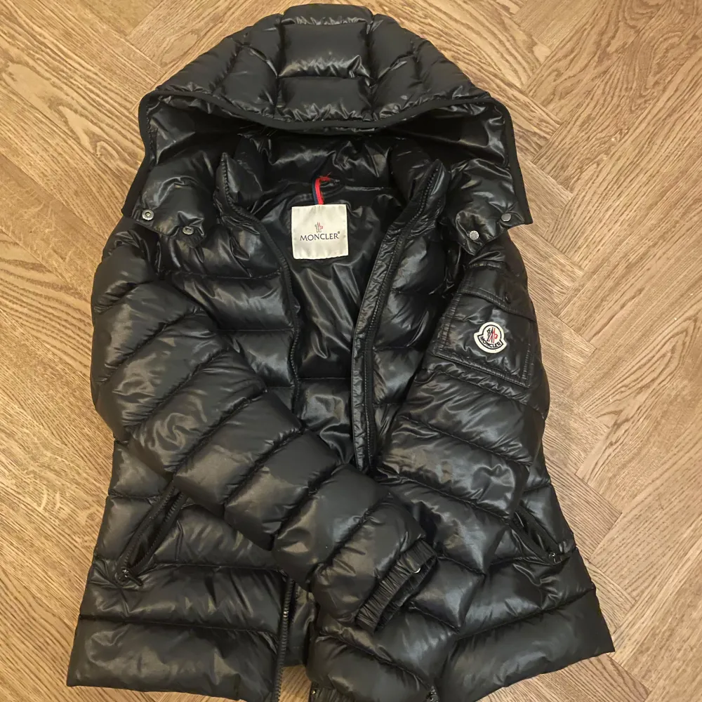 Säljer en snygg svart dunjacka från Moncler. Jackan har en dragkedja framtill och en logga på ärmen. Den är i mycket bra skick och passar perfekt för både höst och vinter. Köpt på NK 2023. Nypris 10.355 kan gå ner i pris vid snabb affär☺️. Jackor.