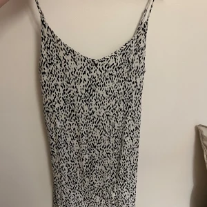 Svartvit prickig klänning - Säljer en superfin svartvit prickig klänning med smala axelband. Perfekt för sommardagar eller en avslappnad fest. Klänningen har en enkel och stilren design som gör den lätt att matcha med olika accessoarer.