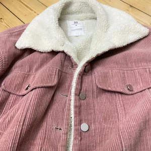 Rosa manchesterjacka från Sunny33 - Säljer en superfin rosa manchesterjacka från Sunny33. Den har en mysig teddyfoder och knappar framtill. Perfekt för kyliga dagar och ger en snygg retrolook. Jackan är i mycket bra skick och kommer från deras Winter Collection.