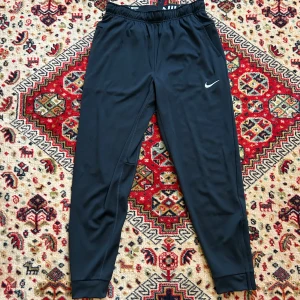 Nike träninsbyxor - Svettiga svarta träningsbyxor från nike🔥🔥 köpte för behövde till idrotten i skolan men sket i idrotten #toocoolforschool 😈🥶💯 jag ogillade sen hur dom satt på mig och dom kommer inte till användning, så säljer dom istället🤗 dom är ju då alltså inte använda, endast testade. Fickorna har dragkedjor så man tappar inte saker, finns också dragkedjor vid benet. byxorna e perfekta för när man ska träna hårt‼️‼️ skriv för fler frågor❤️❤️