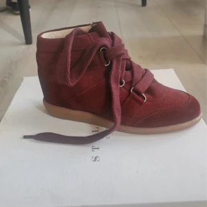 Vinröda sneakers med snörning - Snygga vinröda sneakers med inbyggd klack i mocka med snörning framtill. Liknar marant skorna! De har en bekväm gummisula och en stilren design som passar perfekt för höst och vår. Skorna är i mycket bra. Aldrig använda, Nypris 3000kr! 