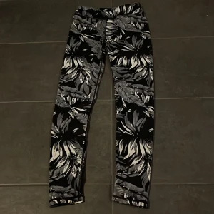 Svartvita mönstrade leggings - Snygga svartvita leggings med ett coolt blommönster. Perfekta för både träning och vardag. Tillverkade i polyester och elastan för en skön och stretchig passform. Passar perfekt för dig som vill ha något bekvämt men ändå stilrent. 🖤🤍