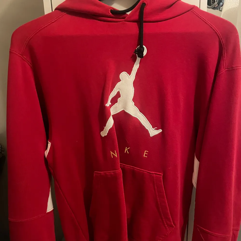 Säljer en snygg röd hoodie från Nike med det klassiska Jumpman-loggan på framsidan. Den har en stor ficka framtill och justerbar huva med svarta snören. Perfekt för kyliga dagar eller som en stilren vardagströja. Passar både till träning och chill.. Tröjor & Koftor.