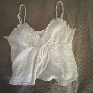Vit volangtopp med rosett 🤍 - Jättesöt vit topp med struktur o volang🥹 i storlek xs-s men stretchig i materialet!!