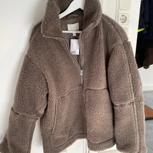 Trendiga hm teddy jackan i pile - Säljer den super virala teddy jackan helt ny från hm! Slutsåld överallt, köpte för 549kr men den var lite för stor för mig. Storlek M, prislappen sitter kvar och den är helt oanvänd. Den nya färgen, jättefin.