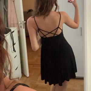en enkel svart klänning med öppen rygg. Klänningen är aldurg använd, bara för bild.