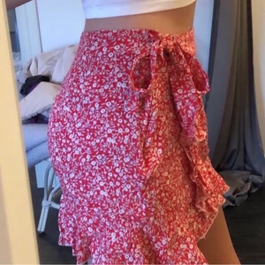 Billig kjol - En röd jättesnygg kjol med vita blommor, volang och en rosett man knyter själv❤️❤️ superfin nu på sommaren🤩