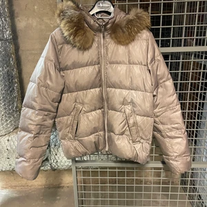 Bomboogie dunjacka I beige  - En beige dunjacka med pälskrage i strl 38. Lite skitig på jackärm kan eventuellt gå bort efter en tvätt. Stor i storlek och otroligt skön.