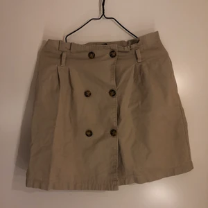 Beige kjol - Beige kjol med knappar. Storlek 36.