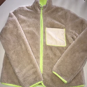 Teddyjacka strl.S - En ljus Teddyjacka med neon-gröna detaljer längt ficka, dragkedja, ärmslut och även längt ner på jackan. Stretchigt material. 