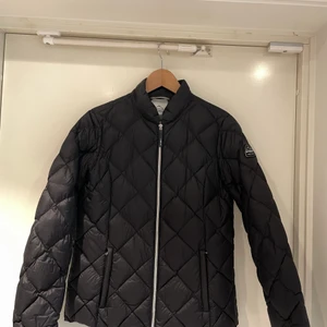 Dunjacka McKinley - Svart dunjacka som endast är använd ett fåtal gånger. Den är i superfint skick. Den är tunn så väldigt smidig att använda men den värmer ändå.