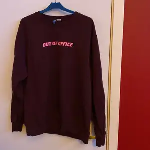 Mörkröd sweatshirt från H&M i storlek M med tryck där det står Out of office i rosa