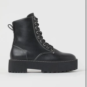 Kängor - Ett par svarta kängor i läderimitation i platå med vita sömar och dragkedja.