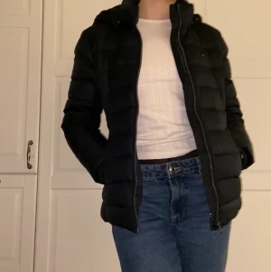 Tommy Hilfiger dunjacka - Dun jacka från Tommy Hilfiger. Är i färgen ”black swan” men upplevs ibland som väldigt mörk marinblå. Jackan är endast använd under en vinter och finns inga tecken på användning, som ny. Både pälsen kan tas av från luvan men även luvan går att ta av.