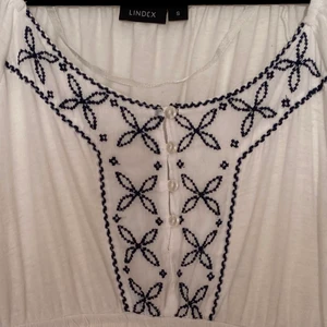 Vit top med blå stickning - Vit top med blå stickning, Strl S. Resor under bysten. Sitter fint på. Normal i strl. Djur- och rökfritt hem. Bra skick. Finns i Hamburgsund men kan efter ök tas med för avlämning i Ua/Gbg/Thn.