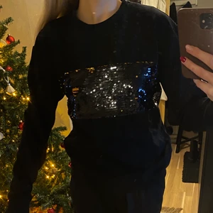 Svart sweatshirt med paljetter - En svart mjuk sweatshirt med paljetter på bröstet. Strl S