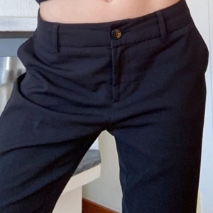 Svarta lågmidjade kostymbyxor - Säljer mina svarta lågmidjade kostymbyxor som tyvärr är för stora för mig. Håller i dem i midjan på bilderna. Midjemåttet är ca 84 cm och innerbenslängden är 81 cm💕 köparen står för frakten❣️