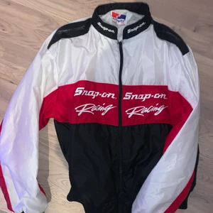 Snap on racing vindjacka  - Sjukt snygg vindjacka köpt på en vintagebutik. Fint skick, gillar färgerna man känner sig cool i den. Storlek xl snyggt oversize på mig som är xs