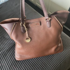 DKNY väska brun - Brun DKNY hand/axelväska med dragkedjor som går att dra in. Knappt använd, bra skick. Frakt tillkommer 66kr.🤎