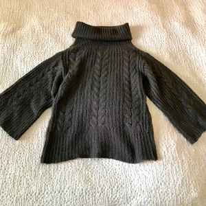 Stickad polotröja, strl M - En mysig, stickad tröja från Vila Clothes i storlek M. Ärmarna är vida och med 3/4 längd och tröjan har en rätt stor polokrage. Färgen är en nyans av mörkgrå, nästan svart, med lite grönbruna undertoner. Tröjan är använd och är lite noppig men bra kvalitet i övrigt. Hör gärna av dig vid frågor :)