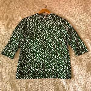 mörkgrön, 60-tals-inspirerad tröja med vitt möster, strl M. Stretchigt och luftigt material. Ärmarna är 3/4 längd. Oanvänd.